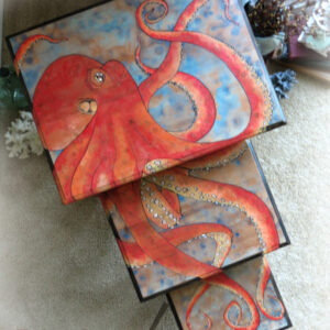 red pacific octopus hand painted onto a set of nesting tables. The blues, reds and oranges burst with color on the table top as the legs of the pieces are pure mahogany with a ebony glaze finish.