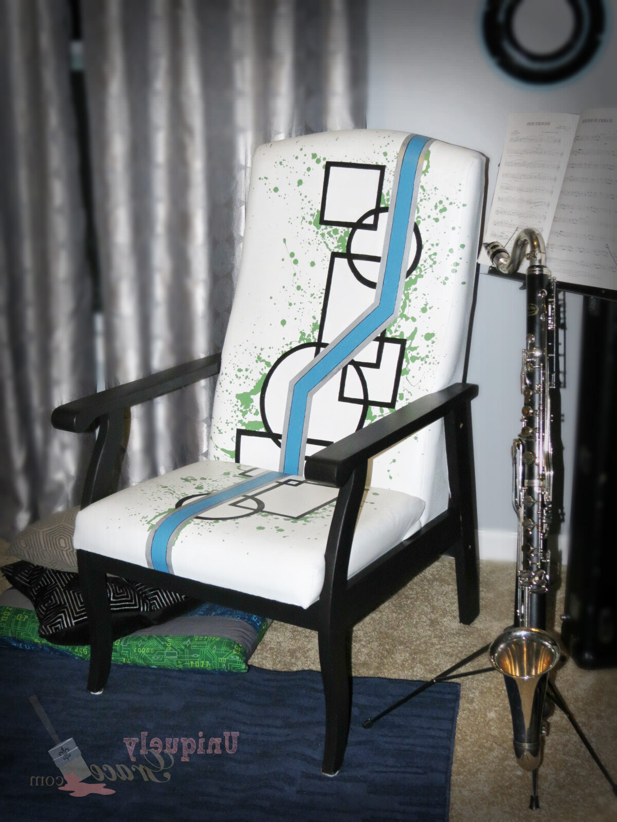 Geometric painted chair. Black with white background and splatters of greens and a blue zig zag stripe. Refinished by Uniquely Grace