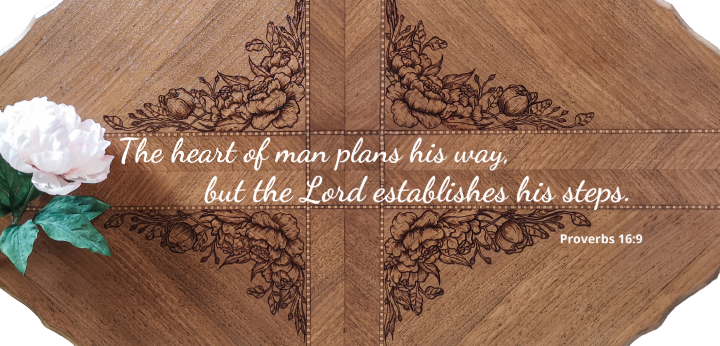 Beautiful wood table top from birds eye view with peony flower design and the scripture Proverbs 16:9 "The heart of man plans his way, but the Lord establishes his steps"